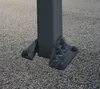 Close-up of the base of a dark gray metal post bolted to the ground. Voir les images du produit