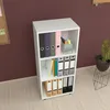 A white bookshelf with various office supplies and binders on its shelves, placed against a dark brown wall. Náhled obrázku produktu
