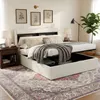 A bedroom scene featuring a white upholstered bed with storage, a nightstand, a lamp, and a rug. Anteprima dell’immagine prodotto