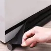 A hand is shown attaching a black foam draft stopper to the bottom of a white object, likely a door or window frame. Náhled obrázku produktu