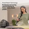 A woman is ironing clothes with a steam iron. A steam generator iron base is visible on the left. Náhled obrázku produktu