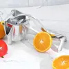 A manual juicer with oranges and a tomato on a marble countertop. Náhľad obrázku produktu