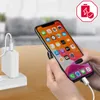 A person is holding an iPhone that is plugged into a white charger and cable. Produktbild-Vorschau