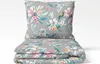 A folded duvet and pillow with a floral and bird pattern on a light gray background. Produktbild-Vorschau