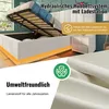 A white upholstered bed with its storage compartment open, showcasing a hydraulic lift system and a bedside table. The image also features a close-up of textured fabric and marketing text. Produktbild-Vorschau