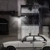 A white car parked in front of a building during a thunderstorm with lightning. Voir les images du produit