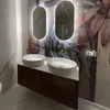 A modern bathroom with a double vanity, featuring two vessel sinks, brass faucets, and a tropical-themed wallpaper. Produktbild-Vorschau