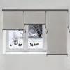 A window with roller blinds partially covering a snowy landscape with sheep. Náhled obrázku produktu