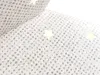 A close-up view of a white fabric with silver glitter and small star shapes. Produktbild-Vorschau