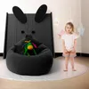 A young girl stands next to a large beanbag chair in a child's room, with a black bunny-themed headboard behind the beanbag. Voir les images du produit