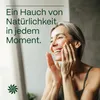 A woman is smiling and touching her face, with text overlay. Produktbild-Vorschau