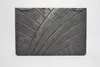 A rectangular, dark gray cast iron plate with a decorative, curved line pattern is shown against a white background. Voir les images du produit