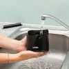 Hands washing a black knock box under a running faucet in a kitchen sink. Náhled obrázku produktu