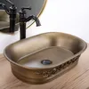 A close-up shot of a bronze vessel sink with a black faucet, placed on a wooden surface. Náhľad obrázku produktu