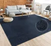 A living room scene with a dark blue rug, a gray sofa, a white coffee table, and decorative poufs. Produktbild-Vorschau