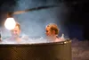 Two people relaxing in a hot tub outdoors at night, with steam rising. Náhled obrázku produktu