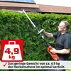 A man is using a long-handled hedge trimmer to trim a tall hedge in front of a house with solar panels. Produktbild-Vorschau