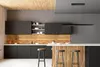 A modern kitchen with dark cabinets, a wooden backsplash, and a breakfast bar with stools. Produktbild-Vorschau