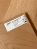 A close-up of a wood-look flooring plank with a product label attached. Produktbild-Vorschau