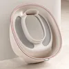 A close-up, angled view of a beige and gray baby potty seat, leaning against a light gray wall. Produktbild-Vorschau
