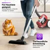 A person is vacuuming a floor with a red and black vacuum cleaner, while a fluffy orange cat sits nearby, looking at the camera. The scene suggests the vacuum is pet-friendly and quiet. Produktbild-Vorschau