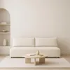 A minimalist living room scene featuring a cream-colored sofa and a round coffee table. Produktbild-Vorschau