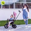 A woman pushing a pink tricycle with a baby in it. Produktbild-Vorschau