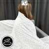 A person is wrapped in a white blanket on a sofa. Náhled obrázku produktu