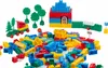A collection of colorful building blocks, including a house, a train, trees, and a fence, scattered on a white surface. Náhľad obrázku produktu