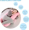 A woman is sleeping on a bed, using a U-shaped pillow. Produktbild-Vorschau