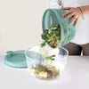 A person is pouring salad from a salad spinner basket into a salad spinner bowl. Produktbild-Vorschau