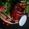 A jar of preserves with a spoon and some berries on a rope mat. Anteprima dell’immagine prodotto