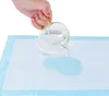 A hand is pouring liquid from a glass onto a hygienic absorbent pad. Produktbild-Vorschau