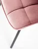 A close-up view of a pink upholstered chair seat and one black metal leg. Náhled obrázku produktu