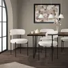 A dining room setting with chairs around a table, featuring a painting and pendant lights. Produktbild-Vorschau