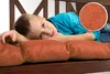 A young boy is lying on a bench cushion. Produktbild-Vorschau