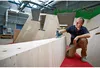 A man is using a Bosch jigsaw to work on a wooden structure in a workshop. Voir les images du produit