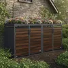 A four-unit trash can enclosure with a planter on top, set against a stone wall and surrounded by greenery. Produktbild-Vorschau