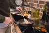 A person is cooking in a kitchen, with various spices and cooking ingredients visible. Náhľad obrázku produktu