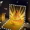 A pop-up birthday card with a lit-up cake design, set on a checkered surface with a candle in the background. Podgląd zdjęcia produktu