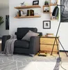 A modern living room scene with a black armchair, a wooden nightstand, and shelves on the wall. Produktbild-Vorschau