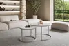 A modern living room with a sectional sofa, coffee tables, and a large window overlooking a garden. Produktbild-Vorschau