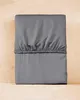 A folded gray fitted sheet is placed on a light brown wooden surface. Anteprima dell’immagine prodotto