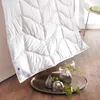 A white duvet is laid out on a wooden floor, with decorative items on a tray in the foreground. Produktbild-Vorschau