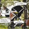 A stroller is shown outdoors in a park-like setting with a person in the background. Produktbild-Vorschau