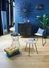A stylish living room with blue walls, wooden floor, and various furniture pieces including a cabinet, chair, tables, and floor cushions. Náhled obrázku produktu