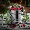 A stainless steel steamer pot filled with raspberries and blueberries, set on a rustic wooden table with scattered berries and greenery. Produktbild-Vorschau