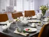 A dining table set for a tea party with porcelain dishes, teapots, cups, saucers, and pastries. Produktbild-Vorschau