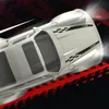 A top-down view of a white drift car with black racing stripes and the word 'DRIFT' on its rear. The car is on a black background with red tire tracks. Náhled obrázku produktu