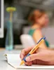 A person's hand is writing in a notebook with a pen. Produktbild-Vorschau